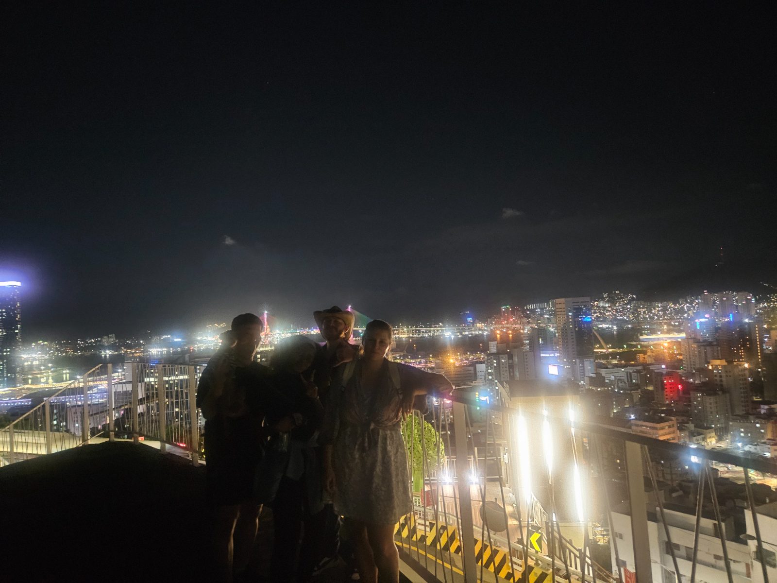 Travelers on a rooftop with the Seomyeon skyline at night