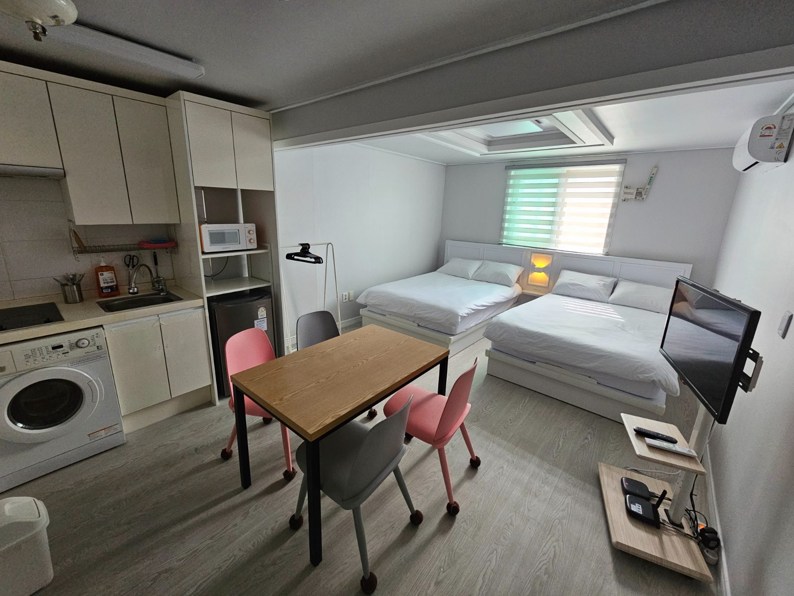 A guesthouse room with two beds and a small kitchen