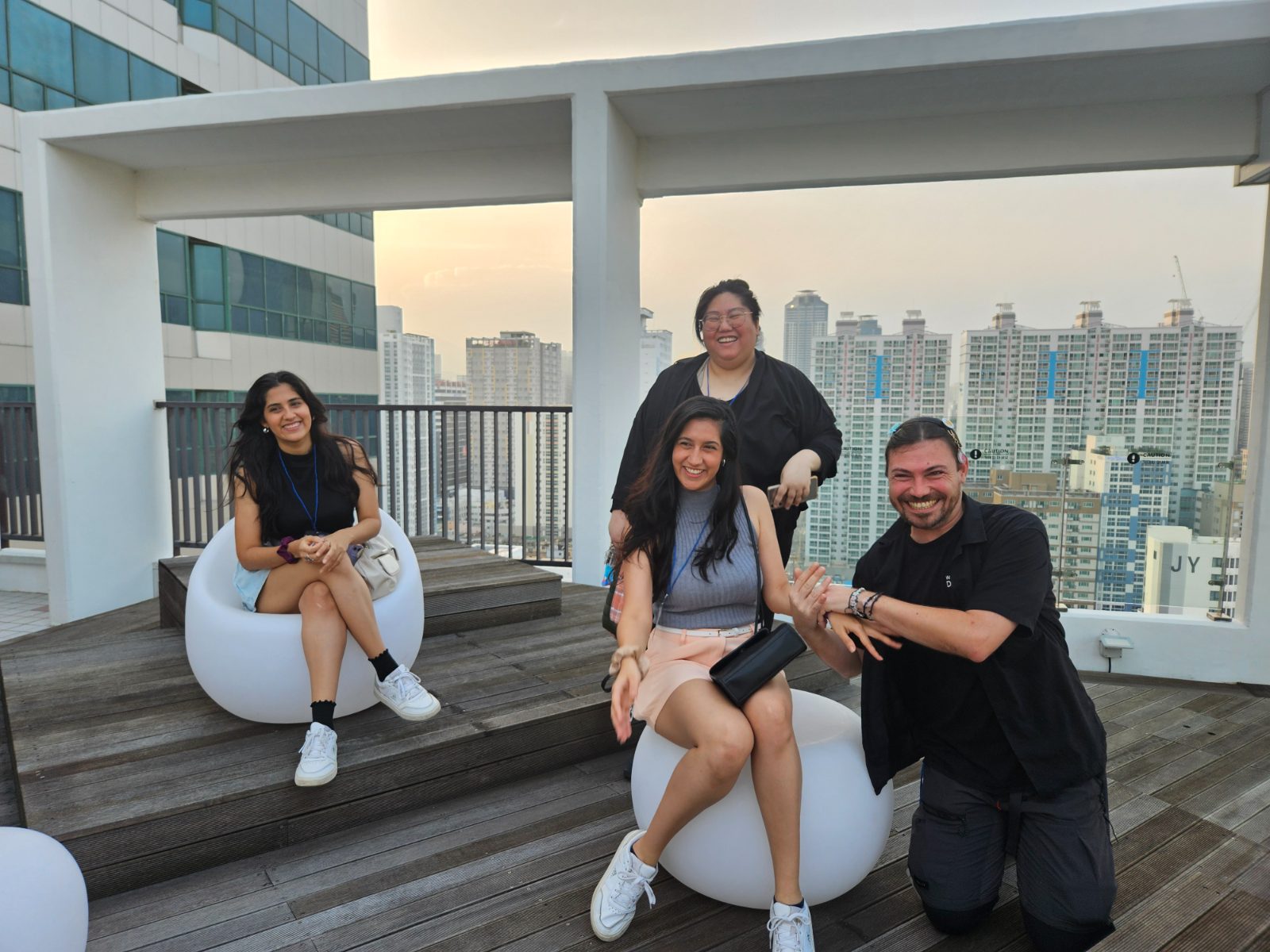 Guests relaxing in a rooftop lounge of a Busan guesthouse with a city view in the daytime.